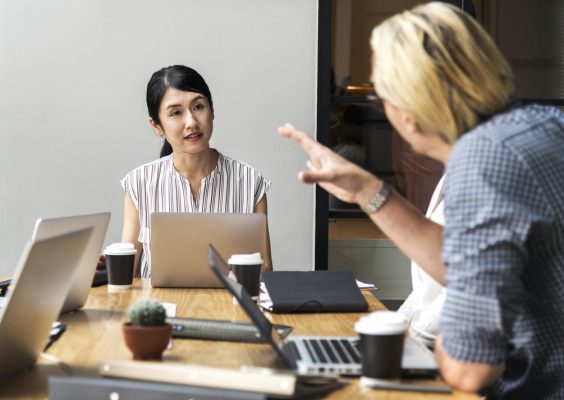 Profesora sentía en mesa con una estudiante